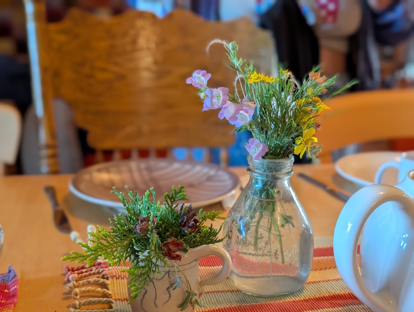 A small glass vase of wildflowers against a warm wood table